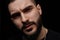 Close-up dramatic portrait of a young serious discontented guy, musician, singer,rapper with a beard on a black isolated