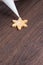 Close up of drawing Christmas snowflake sugar cookie on wooden table background with icing