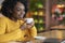 Close up of dreamy black girl enjoying cup of coffee