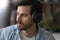 Close up dreamy man in headphones looking to aside