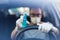 Close up of driver in protective mask with hands wearing rubber gloves on steering wheel holding alcohol sanitizer sprayer, covid-