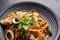 Close-up of drunken spaghetti with seafood with shrimp, squid, clams, chili, and basil. Healthy Thai Asian food in a plate on a