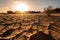 close-up of dry and cracked sand dunes, with the sun shining in the background