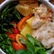 Close up dry paper noodles soup bowl, tofu, pine apple, tomato, water spinach