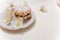 Close up of dulcet sand tart cookie with powdered sugar on plate with jasmine flowers on white table. Sweet pastry, spring blossom