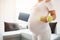 Close-up on a dumbbell. Pregnant woman holding a yoga mat at her home. Active sporty life, wellness.