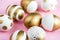 Close up of easter eggs colored with golden paint. Various striped and dotted designs. Pink background.