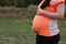 Close-up of Eastern Asian Chinese pregnant woman\'s belly, grass meadows as background, in forest garden outdoor nature