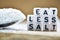 Close-up of Eat less salt text written with plastic letters near a salt spoon