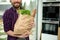 Close-up eco paper bag, craft cardboard packet with greens, salads, healthy food, whole grain baguette bread in hands of handsome