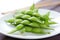 close-up of edamame pods on white plate