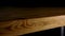 Close-up of edge of wooden table on dark background. Stock footage. Beautiful smooth edge of brown wooden table lit by