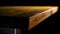 Close-up of edge of wooden table on dark background. Stock footage. Beautiful smooth edge of brown wooden table lit by