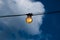 Close up of an Edison-style filament on a light bulb against a cloudy sky. Energy crisis