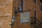 Close-up of elaborate Hotel plate, made of iron, stuck in stone wall and lamp in Orvieto.