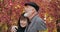 Close-up elderly couple, bearded husband with gray haire hugging sad wife with bouquet of autumn leaves, consoling