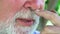 close-up. An elderly man with a gray beard and a false jaw talks.