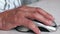 Close-up of an elderly man`s hand clicking a computer mouse while working on a gadget. Adult seniors and digital devices. Selectiv