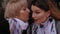 Close-up of an elderly woman whispering something in the ear of her daughter.