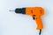 Close-up electric orange drill screwdriver on white background. View from above