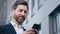 Close-up elegant handsome bearded man holding phone sends email communicates on internet successful businessman planning