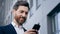 Close-up elegant handsome bearded man holding phone sends email communicates on internet successful businessman planning