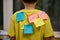 Close-up elementary school student with paper for notes glued on yellow t-shirt with inscriptions: Motivation Knowledge