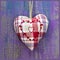 Close-up of embroidered heart shape on purple wooden surface.