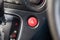 Close-up of an emergency button with a white triangle icon on the red plastic of a car dashboard. Signal of breakage, problem, or