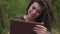Close-up emotional face of lovely brunette woman playing on a digital tablet while sitting on a wooden pier in summer