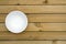 Close up of an empty white bowl on a wooden table - directly above.