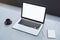 Close up of empty white laptop on concrete desktop with coffee cup, notepad, pen, mock up place on screen, blurry background. 3D