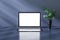 Close up of empty white laptop frame screen on abstract shiny workplace background with reflections and vase with green plant.