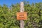 Close up of an engraved wooden Anns Point sign against green leaves and blue sky