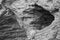 Close up of eroded hole in cliff rock texture background in black and white