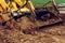 A close-up excavator loads soil into the bucket for further road installation