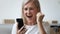 Close up excited older woman shouting, using phone, celebrating success