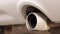 Close-up of the exhaust pipe of a working white car.