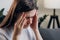 Close up of exhausted frustrated young female sitting on sofa massaging nose bridge temples. Stressed unhealthy girl feeling tired