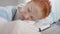 Close-up of exhausted overwhelmed doctor sleeping on table in hospital. Portrait of beautiful redhead Caucasian woman