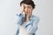 Close up of exhausted young girl with dark short hair holding face with hands, suffering from headache after big amount