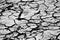 Close up of extremely dry, cracked soil ground texture in black and white