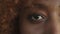 Close up, eye of an african american young woman opening and looking at the camera