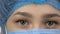Close-up eyes of young female surgeon doctor or intern wearing protective mask and hat.