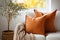 Close up of fabric sofa with terra cotta pillow against window and white wall. AI generate