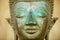 Close up of a face of an ancient copper Buddha statue outside of the Hor Phra Keo temple in Vientiane, Laos.