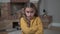 Close-up face of an angry caucasian girl in mustard sweater with crossed hands on chest. Dissatisfied child shaking her