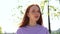 Close-up face of beautiful red-haired girl drinking water from bottle outdoors on bright sunny day.