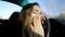 Close-up face of beautiful young Caucasian woman yawning and sleeping on car steering wheel. Portrait of exhausted tired