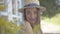 Close-up face of beautiful young woman in straw hat looking at the camera smiling happily outdoors. Emotion, rural